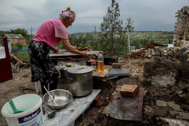 Lubov (67), priprema obrok na ostacima peći gdje je nekada bila njena kuhinja u selu Bohorodične, Donecka regija.