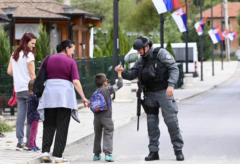 Naoružani kosovski policajac pozdravlja dječaka dok patrolira selom Banjska na Kosovu u kojem se naoružana srpska skupina od tridesetak ljudi sukobila s policijom.