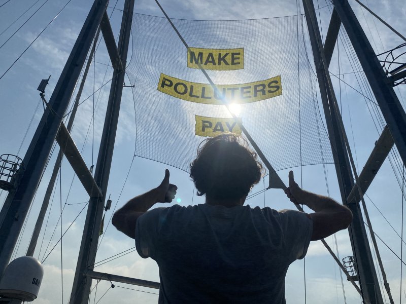 Član posade Greenpeaceovog broda Rainbow Warrior pokazuje transparent na kojem piše 'Neka zagađivači plate' dok je usidren u luci Manila na Filipinima.