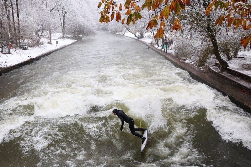 Surfer 'jaše' val na potoku Eisbach u snijegom prekrivenom parku Engleski vrt u njemačkom gradu Münchenu.