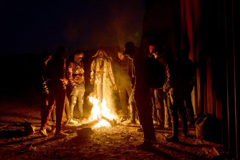 Migranti iz Senegala griju se uz vatru dok čekaju da ih obradi američka granična patrola u Arizoni.