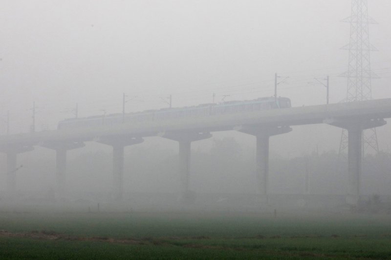 Vlak prolazi kroz gustu maglu u indijskom New Delhiju.