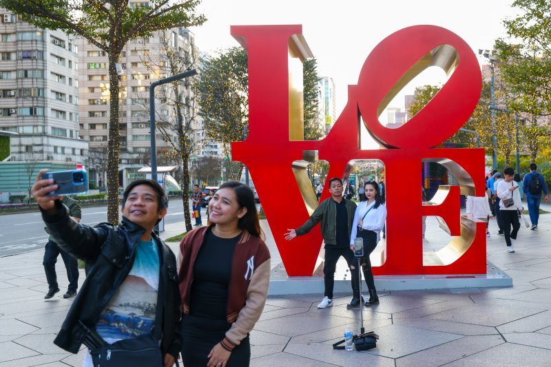 Zaljubljeni parovi poziraju ispred znaka na kojem piše Ljubav (engl. Love) na Valentinovo u tajvanskom Taipeiju.