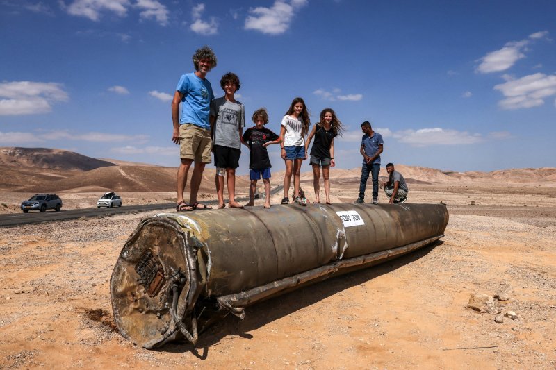 Ljudi stoje na vrhu ostataka iranske rakete u pustinji Negev u blizini Arada, nakon iranskog raketnog napada na Izrael.