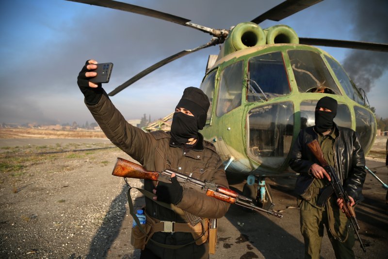 Pripadnici sirijske opozicije rade 'selfie' ispred helikoptera na vojnom aerodromu kod Alepa kojeg su zauzeli proteklih dana.