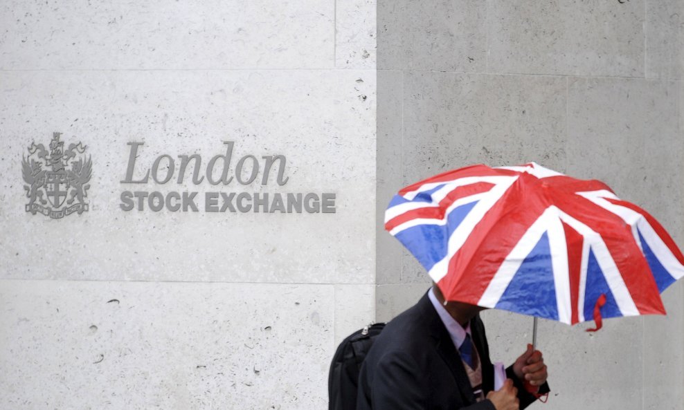 A worker shelters from the rain as he passes the London Stock Exchange in the City of London at lunchtime October 1, 2008. REUTERS/Toby Melville/File Photo